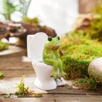 A whimsical frog statue in a resin toilet