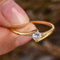 Inel de lux de culoare aurie cu design ce susține o piatră albă strălucitoare